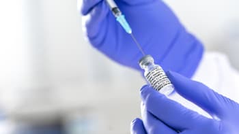 A syringe extracting COVID vaccine from a vial.